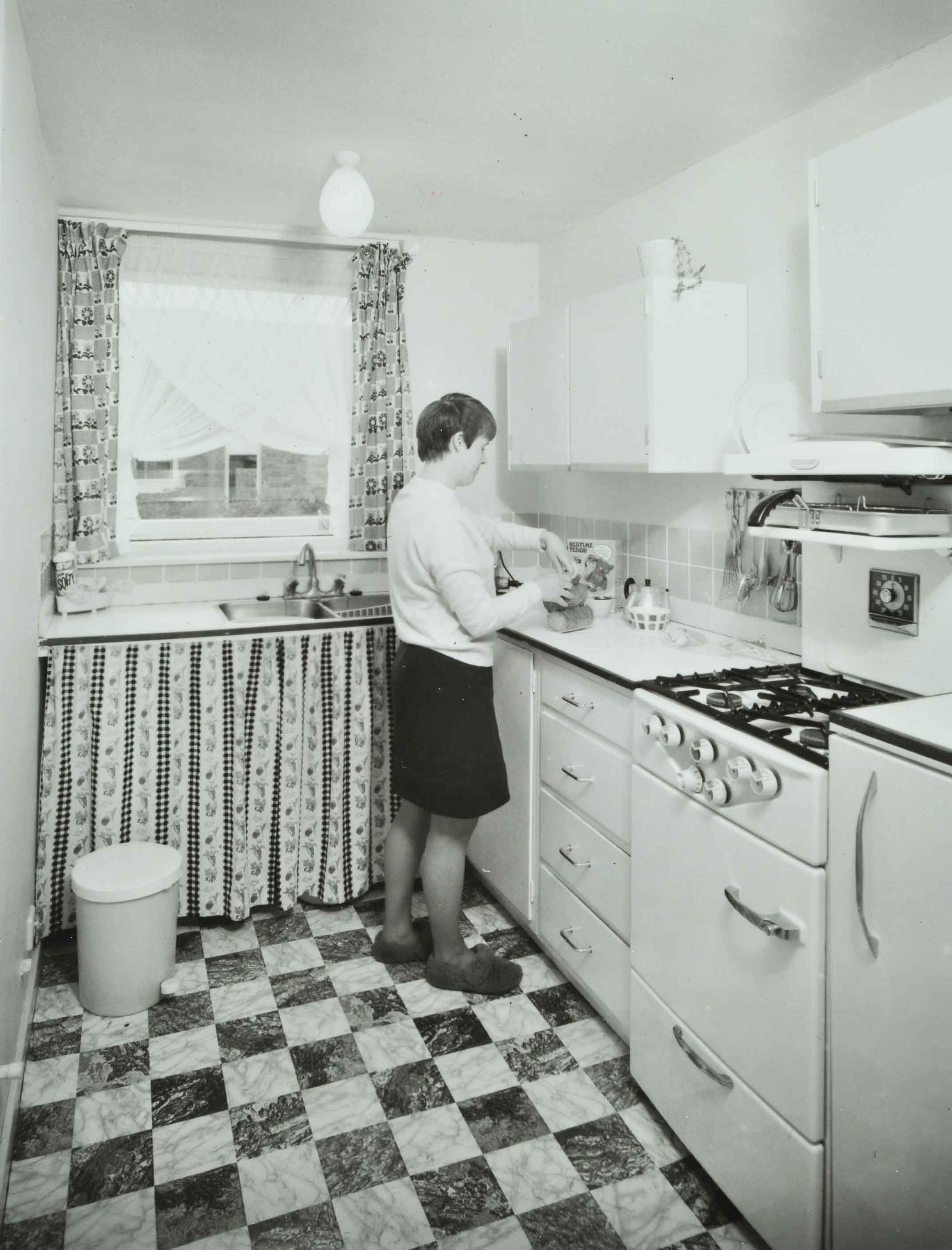 Woman standing in the kitchen at an Andover Town Development, 1969
